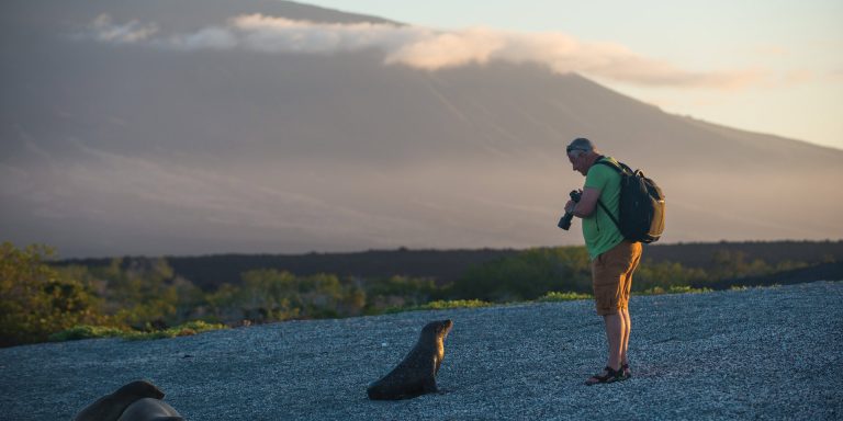 Contours Travel- Man with a seal by the beach in Galapagos